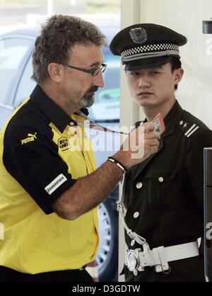 Équipe de formule un patron britannique Eddy Jordan passe un agent de sécurité chinois comme il arrive dans le paddock du circuit de course de formule un nouveau à Shanghai, Chine, le jeudi, 23 septembre 2004. Le Grand Prix de Chine, la toute première course de Formule 1 sur le sol chinois, aura lieu le dimanche 26 septembre 2004. Banque D'Images