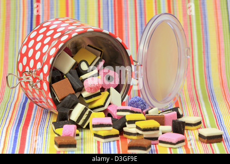Bonbons réglisse dans un conteneur de couleur tournée vers le haut contre un fond coloré. Banque D'Images