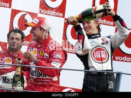 (Dpa) - Ferrari pilote de Formule 1 Rubens Barrichello du Brésil (C) jubilates et est arrosé au champagne par British BAR-Honda Jenson Button pilote (R) après la fin de la Grand Prix d'Italie à Monza, Italie, le 12 septembre 2004. Barrichello a remporté la course avec son coéquipier Michael Schumacher de l'Allemagne venant en deuxième Ferrari de donner son 9e doublé de la saison de course. B Banque D'Images