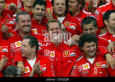 (Afp) - L'Allemand Ferrari pilote de Formule 1 Michael Schumacher (C) célèbre avec tête de Ferrari Jean Todt (L) et le reste de son équipe après la formule un Grand Prix de Belgique à Spa, 29 août 2004. Schumacher a terminé en deuxième place dans le Grand Prix, remportant un nombre sans précédent de septième titre de champion du monde en dépit de ne pas gagner pour seulement la deuxième fois en 14 courses cette saison. Banque D'Images