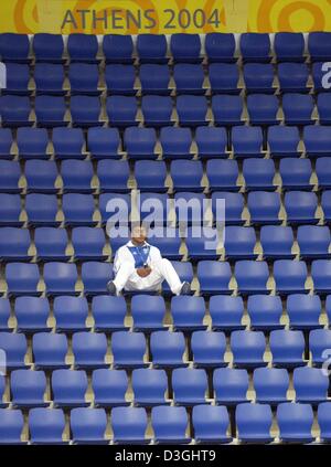 (Afp) - Un homme est assis entre les sièges vides à l'Ano Liossia hall olympique au cours de la session du matin de la compétition de judo lors des Jeux Olympiques de 2004 à Athènes, Grèce, le 16 août 2004. Banque D'Images