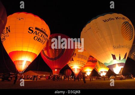 (Afp) - avec des flammes que les pilotes leurs montgolfières glow en face du ciel nocturne dans le cadre de la 10e 'Saxonia International Balloon Fiesta" à Leipzig, Allemagne, 29 juillet 2004. Plus de 130 pilotes venus de 9 pays ont participé à l'événement avec des ballons dans ces formes insolites comme une caisse de bière ou d'un cornet de crème glacée. Banque D'Images