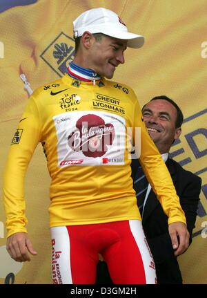 (Afp) - le cycliste Français Thomas Voeckler (avant) de l'équipe Brioches La Boulangere sourit comme Bernard Hinault awards lui avec un corsage après avoir réussi à défendre le maillot jaune du meneur pour la quatrième fois au cours de la huitième étape du Tour de France à Quimper, France, le 11 juillet 2004. La scène couvre une distance de 168 km de Lamballe à Quimper. Banque D'Images