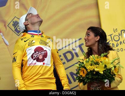 (Afp) - le cycliste Français Thomas Voeckler (L) de l'équipe Brioches La Boulangere regarde comme il reçoit un bouquet de fleurs après avoir réussi à défendre le maillot jaune du meneur pour la quatrième fois au cours de la huitième étape du Tour de France à Quimper, France, le 11 juillet 2004. La scène couvre une distance de 168 km de Lamballe à Quimper. Banque D'Images