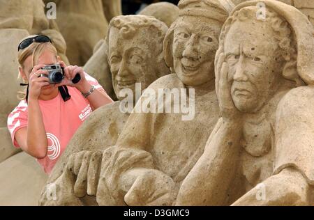 (Afp) - Un employé prend une photo de trois statues de sable représentant le 'Nike Air anciens vendeurs formateurs' sur la plage de Detmold, Allemagne, le 5 juillet 2004. 75 sculpteurs soi-disant de 13 pays travaillent sur leurs sculptures pour le 3ème festival de sculptures de sable allemand, monde de sable, qui sera sous le thème de "myth d'Olympie' cette année. Le festival avec le lan Banque D'Images