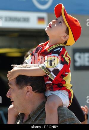 (Afp) - un petit ventilateur Ferrari, assis sur les épaules de son père, examine curieusement le ciel au-dessus de lui sur la piste de course de Formule Un à Montréal, Canada, 10 juin 2004. Les visiteurs sont autorisés à marcher sur la piste lors de la traditionnelle journée portes ouvertes, quelques jours avant le début du Grand Prix du Canada, le dimanche 13 juin 2004. Banque D'Images