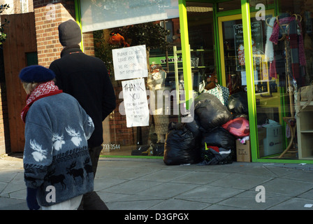 Dons en sacs s'entassent dans un magasin de charité ou de l'entrée du magasin en Angleterre, Royaume-Uni. Remarque signe sur fenêtre. Banque D'Images