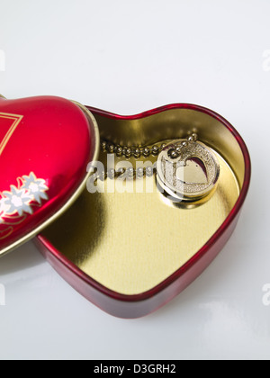 Un cœur en acier inoxydable doré avec un coeur miniature key-chain isolé sur fond blanc Banque D'Images