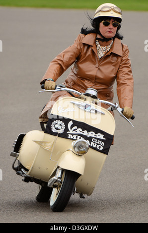 Femme dans des vêtements vintage chevauchant un scooter Vespa classique. Goodwood Revival Banque D'Images