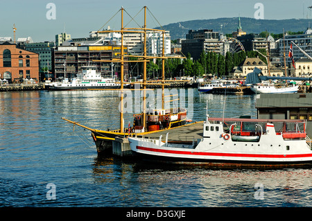 Bateaux amarrés dans le port d'Oslo reflètent le soleil tôt le matin entouré de bâtiments anciens et modernes autour du quai Banque D'Images