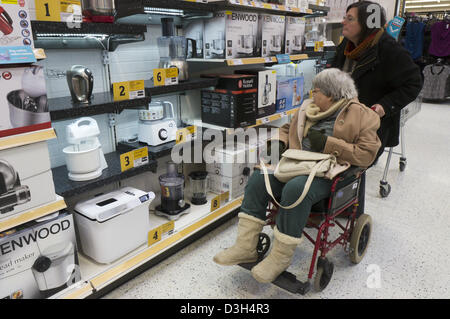 Une vieille dame dans un fauteuil roulant et sa garde ou assistant regarder ustensiles produits électriques dans un supermarché. Banque D'Images