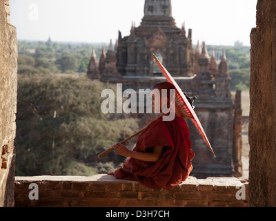 Jeune moine novice et parapluie encadrée dans une arcade Bagan Temple. Banque D'Images