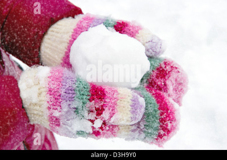 Girl holding a snowball dans sa mains couvertes de mitaines Banque D'Images