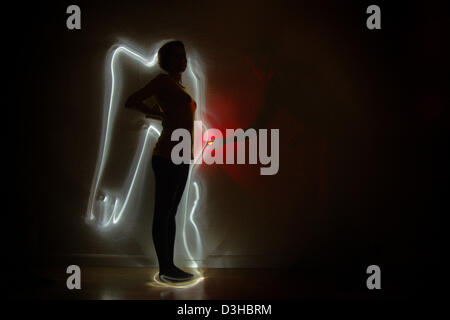 Comité permanent des femmes enceintes femme ange avec point rouge dans son ventre peint avec contour bleu lumière autour de sa silhouette Banque D'Images