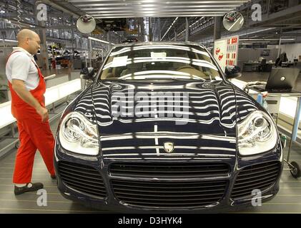 (Afp) - Un employé inspecte la qualité du vernis d'un Cayenne Turbo à l'usine de production Porsche à Leipzig, Allemagne, 6 octobre 2003. Porsche Leipzig a choisi comme lieu de l'assemblée générale du 23 janvier 2004, afin de souligner l'importance de cette production pour l'entreprise. L'usine de production de Leipzig assemble le Cayenne Turbo qui besto Banque D'Images