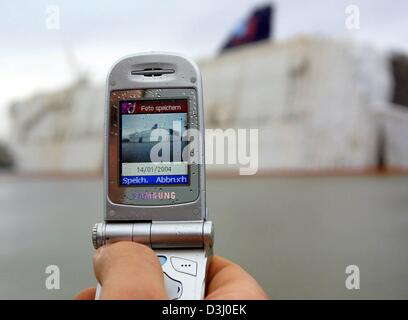 (Afp) - Une photo de l'un paquebot de croisière 'Fierté de l'Amérique", qui est toujours en cours de construction et l'inscription d'un côté, est pris avec l'appareil photo numérique d'un téléphone mobile combiné dans le chantier naval Lloyd à Bremerhaven, Allemagne du nord, le 14 janvier 2004. Dans la nuit précédente, les 280 m de long bateau de croisière a été frappé par un grain, l'inclinant contre la jetée. On peut supposer que l'eau est entrée throu Banque D'Images