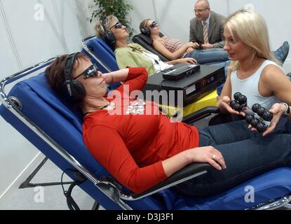 (Afp) - un Shiatsu-Master Schablowski Swetlana explique-fauteuil de massage à un visiteur au stand du marché de la société au cours de l'brainlight salon du bien-être à Leipzig, Allemagne, 25 septembre 2003. Les visiteurs sont le port de lunettes de soleil et qui simulent l'écoute avec écouteurs pour le murmure de la mer - prévu pour être un aussi près que possible l'imitation d'une journée à la plage. Banque D'Images