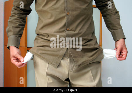 (Afp) - Un homme démontre qu'il est hors de l'argent en montrant son pantalon vide poches à Francfort, Allemagne, 07 mars 2005. Banque D'Images