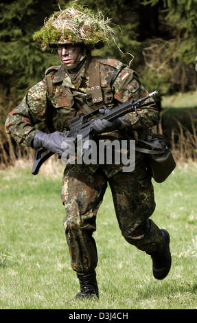 (Afp) - un conscrit de la division d'infanterie de la Bundeswehr, une tenue de camouflage et armé d'un fusil G36, s'exécute sur un champ au cours d'un exercice sur le terrain dans le cadre de la formation militaire de base à la caserne en Knuell Schwarzenborn, Allemagne, 14 avril 2005. Banque D'Images