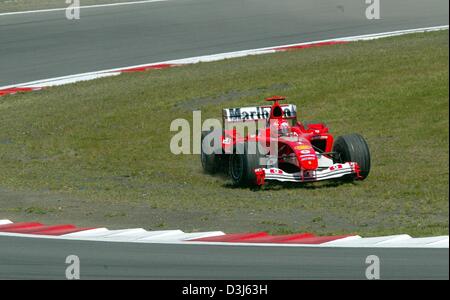 (Afp) - L'allemand champion du monde de Formule 1 Michael Schumacher braque sa voiture de course Ferrari à travers une pastille verte après une rotation au cours de la formation libre le long de la piste de course de Nürburgring, Allemagne, 28 mai 2004. Schumacher a conduit le deuxième meilleur temps. Le Grand Prix d'Europe a lieu au Nürburgring le 30 mai 2004. Banque D'Images