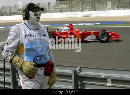 (Afp) - L'Allemand Michael Schumacher, la formule 1 vitesses dans sa voiture de course Ferrari passé un cours de comté, qui porte un masque à l'épreuve au cours de la formation gratuite à la piste de course de Nürburgring en Allemagne, vendredi, 28 mai 2004. Schumacher a conduit le deuxième meilleur temps. Le Grand Prix d'Europe a lieu au Nürburgring le 30 juin 2004. Banque D'Images