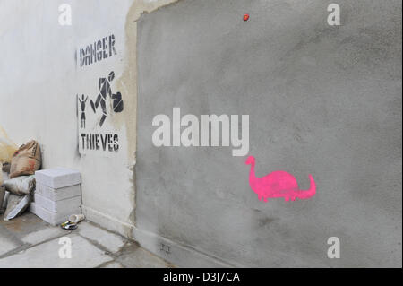 Wood Green, Londres, Royaume-Uni. 20 février 2013. Les mots "danger Thieves' ont été inscrit à côté du trou cimenté où le Banksy murale a été sur le mur de Poundland à Wood Green. Un petit dinosaure rose a également été au pochoir sur le ciment. Banque D'Images