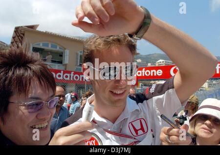 (Afp) - pilote de Formule 1 britannique Jenson Button (BAR-Honda) promenades à travers un groupe de fans vers l'enclos à Monaco le 19 mai 2004. Le Grand Prix de Formule 1 de Monaco aura lieu le dimanche 23 mai 2004. Banque D'Images
