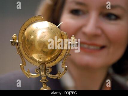 (Afp) - Wievelhove Hildegarde, le chef de la Musée Hülsmann, a un regard étonné sur son visage alors qu'elle contemple un cadran solaire en forme de globe du 17e siècle faite de laiton doré lors d'une exposition à son musée à Bielefeld, Allemagne, 23 avril 2004. Banque D'Images