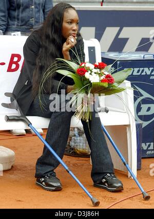 (Afp) - Le joueur de tennis américain Venus Williams avec des béquilles est assis sur un banc sur le centre à Berlin, Allemagne, le 9 mai 2004. En raison de sa blessure, Venus Williams n'a pas pu prendre part à la finale de l'Open allemand. Son adversaire le français, Amélie Mauresmo a gagné le tourmanent sans un match le dimanche 9 mai 2004. Banque D'Images