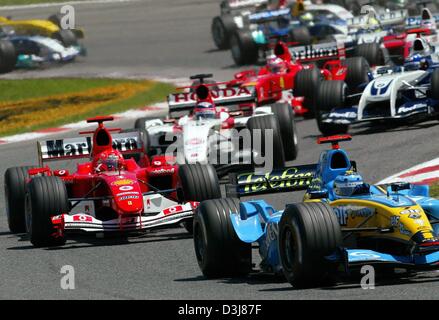 (Afp) - L'Italien Jarno Trulli pilote de formule 1 de Renault (avant) mène le pack dans le premier virage après le début de la Grand Prix d'Espagne sur le circuit de Catalogne près de Barcelone, Espagne, le 9 mai 2004. Trulli est suivie de près par l'Allemand Michael Schumacher dans sa Ferrari rouge. À la fin, Schumacher a remporté la course de Trulli rentre à la maison en troisième. Banque D'Images