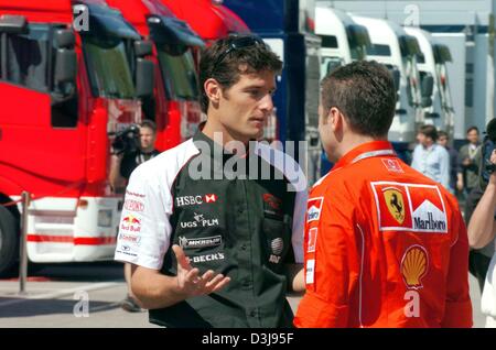 (Afp) - Le pilote de Formule 1 Mark Webber (Jaguar) L'équipe, parle à un mécanicien de Ferrari dans le paddock à la piste de course "Enzo e Dino Ferrari à Imola, Italie', 22 avril 2004. La première course européenne de la saison de F1 aura lieu à Imola avec le Grand Prix de Saint-Marin dimanche prochain. Banque D'Images