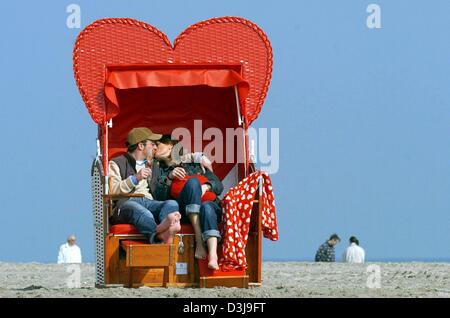 (Afp) - Kerrin (R) et Frank baiser les uns les autres comme ils sont assis en forme de coeur en osier couvert chaise de plage sur la plage de Detmold, Allemagne, 9 avril 2004. Mots-clés : Human-Interest, hum, les gens, les baisers, coeur, couvert/e   plage en osier, président ALLEMAGNE:DEU, fonction, couple Banque D'Images