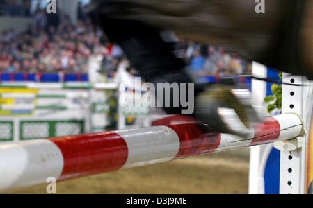 (Afp) - un cavalier et son cheval effacer l'obstacle et éviter de frapper la barre de seulement un pouce lors d'un Tournoi équestre à Neustadt-Dosse, Allemagne, 10 janvier 2004. Banque D'Images