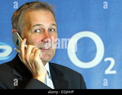 (Afp) - Rudolf Groeger, chef du fournisseur de réseau mobile O2 Germany, pose avec un cellulaire en face de l'O2 logo un jour avant l'ouverture du plus grand salon informatique CeBit à Hanovre, en Allemagne, le mercredi 17 mars 2004. O2 a présenté la première applications UMTS pour le marché allemand. Les nouveaux services UMTS sera disponible au public à partir de l'été. Exhi 6 411 Banque D'Images