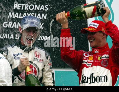 (Afp) Le champion du monde de F1 allemand Michael Schumacher (Ferrari) sprays troisième placé Jenson Button (BAR-Honda/gauche) avec le champagne après avoir remporté le Grand Prix de Malaisie sur le circuit de Sepang près de Kuala Lumpur le dimanche, 21 mars 2004. Schumacher a gagné sa deuxième victoire dans la deuxième course de la saison avec une victoire finale début invulnérables. Banque D'Images