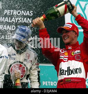(Afp) Le champion du monde de F1 allemand Michael Schumacher (Ferrari) sprays troisième placé Jenson Button (BAR-Honda/gauche) avec le champagne après avoir remporté le Grand Prix de Malaisie sur le circuit de Sepang près de Kuala Lumpur le dimanche, 21 mars 2004. Schumacher a gagné sa deuxième victoire dans la deuxième course de la saison avec une victoire finale début invulnérables. Banque D'Images
