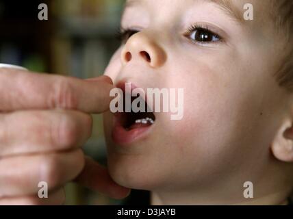 (Afp) - un petit garçon a mis sur les globules de sa langue à la pratique d'un praticien des dans Schoeneck-Kilianstaedten, Allemagne, 29 janvier 2004. Les globules rouges contiennent de la médecine homéopathique. Banque D'Images