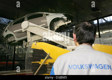 (Afp) - Un employé de Volkswagen (VW) regarde le corps d'une voiture Golf Plus se déplace le long vers la station de peinture à l'usine de montage VW à Wolfsburg, Allemagne, 22 février 2005. VW emploie 103 800 travailleurs en Allemagne dont environ 50 200 travaillent à l'usine de production de Wolfsburg. Banque D'Images