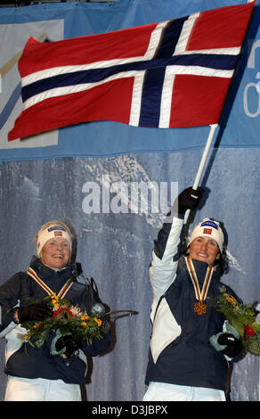 (Afp) - La Norvège a Hilde G. Pedersen et sa coéquipière Marit Bjoergen (R), qui met le drapeau national norvégien, cheer et jubilate au cours de la cérémonie de remise des prix après avoir remporté la médaille d'or chez les femmes de la 6x0,9 km ski de Sprint équipe Événement au Championnat du Monde de ski nordique à Oberstdorf, Allemagne, 24 février 2005. La Norvège a remporté l'avant d'Finnnland et la Russie. Banque D'Images