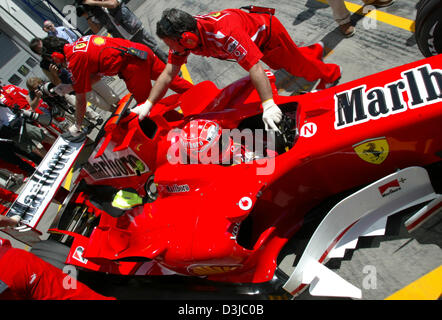 (Afp) - Les mécaniciens de Ferrari pousse l'Allemand pilote de Formule 1 Michael Schumacher Ferrari de retour dans les stands lors de la première session à la pratique du circuit de Nürburgring en Allemagne, Nuerburg, vendredi 27 mai 2005. Le Grand Prix d'Europe a lieu au Nürburgring le dimanche 29 mai 2005. Banque D'Images