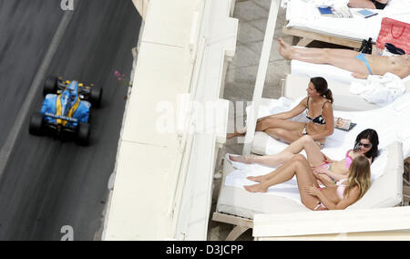 (Afp) - L'Italien Giancarlo Fisichella, pilote de Formule 1 de Renault (L) conduit sa voiture de course tandis que les femmes non identifiées en bikini le soleil sur des lits supplémentaires au cours de la session de formation du Grand Prix de Monaco à Monte Carlo, Monaco, samedi 21 mai 2005. Banque D'Images