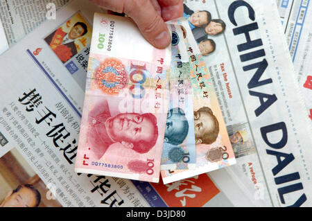 (Afp) - l'image montre une main tenant une banque chinoise note sur les journaux chinois à Beijing, Chine, le vendredi 13 mai 2005. La Banque centrale chinoise a refusé l'augmentation de rumeurs au sujet de la réévaluation de sa monnaie dans les semaines à venir. Selon l'agence de presse officielle chinoise Xinhua de Beijing Gouverneur Zhou Xiaochuan a appelé les spéculations sur un fondement d'une réévaluation de la devise ru Banque D'Images