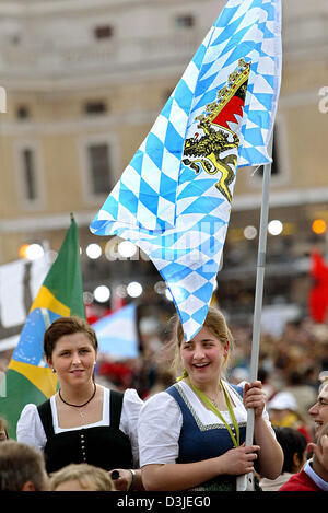 (Afp) - Deux femmes pèlerins de l'Allemagne, vêtu d'un costume traditionnel bavarois, regarde à travers une paire de jumelles pendant le service de l'église sur la Place Saint Pierre au Vatican, à Rome, Italie, 24 avril 2005. Le pape Benoît XVI a été nommé le nouveau chef de l'église catholique romaine, aujourd'hui, le dimanche 24 avril 2005. Autour de 100 000 personnes ont pris part à l'événement. Banque D'Images