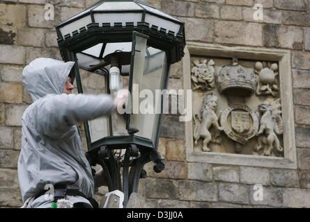 (Afp) - Un homme cleas une lanterne en face du château de Windsor à Windsor, en Angleterre, 6 avril 2005. Le Prince Charles et son partenaire à long terme de Camilla Parker Bowles mariés dans une courte cérémonie à Windsor le 9 avril 2005. Banque D'Images