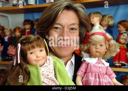 (Afp) - Directeur des affaires de 'Kaethe-Kruse-Dolls' Andrea Kathrin Christenson pose avec deux poupées en face de la photo de Kaethe Kruse (1883-1968), fondatrice de la société, en Allemagne, Donauwoerth, 11 avril 2005. Les poupées faites à la main sont remplis de cheval ou de poils de renne. Un vrai sèche perruque adhère à la tête peinte à la main. La caractéristique des poupées vêtements dans divers designes. La d Banque D'Images