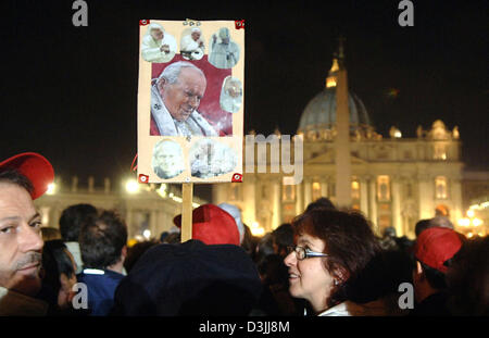 (Afp) - un des fidèles affiche présentant des photos du Pape Jean Paul II pendant qu'ils attendent en face de la Basilique Saint Pierre au Vatican, État de la Cité du Vatican, dans la nuit au 6 avril 2005. Jusqu'au 8 avril, la cathédrale a été ouverte jour et nuit pour les visiteurs du monde entier de sorte qu'ils étaient en mesure de payer leur rendre hommage au défunt pape. Banque D'Images