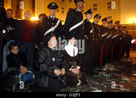 (Afp) - Deux religieuses s'agenouiller dans la rue, à côté d'un groupe d'agents de police, de prier à St Peter's Square à Rome, Italie, le mercredi, 06 avril 2005. Des milliers de fidèles se sont réunis pour rendre un dernier hommage au Pape Jean Paul II dont le service funèbre a lieu le vendredi, 08 avril 2005. Banque D'Images