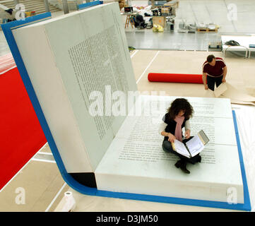 (Afp) - une femme assise sur un livre en bois ouverte qui est de 11 m2 grande pendant les préparatifs de la foire du livre de Leipzig dans le hall vitré au parc des expositions de Leipzig, Allemagne, 14 mars 2004. Le livre est en bois le podium pour la lecture "le canapé bleu" sur laquelle chaque jour toutes les 30 minutes entre 10h00 et 18h00 pour les auteurs, qui sont présentées par les éditeurs de Bertelsmann, le 'Die Banque D'Images