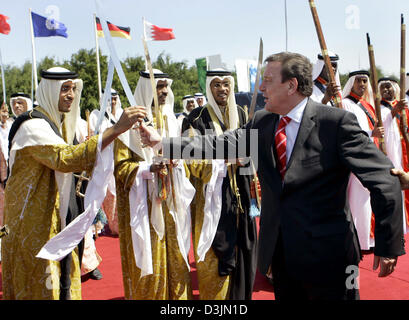 (Afp) - Le Chancelier allemand Gerhard Schroeder est accueillie par un groupe de danseurs de sabre avant la pose de la première pierre pour la construction de l'Université de l'Europe à Manama, Bahreïn, le mercredi 2 mars 2005. Schroeder visite à Bahreïn est partie de sa tournée d'une semaine de sept pays arabes visant à stimuler l'Allemagne Les relations politiques et commerciales dans la région du Golfe. Banque D'Images