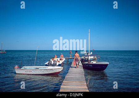 Jetée en bois avec passagers à bord de petits bateaux à moteur partant de Caye Caulker depuis la chapelle de Caye, Belize Banque D'Images